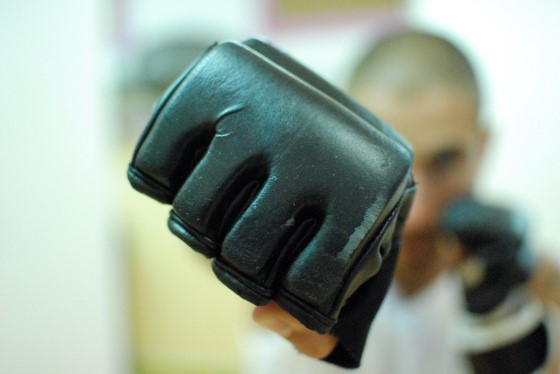 Boxing glove front and center from a man throwing a punch.