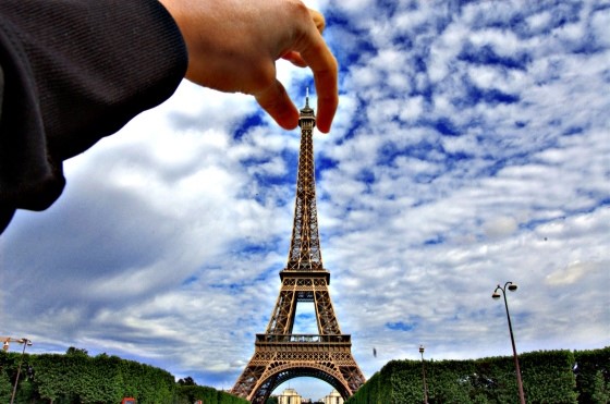 Picture of someone holding the Eiffel Tower in his fingertips.