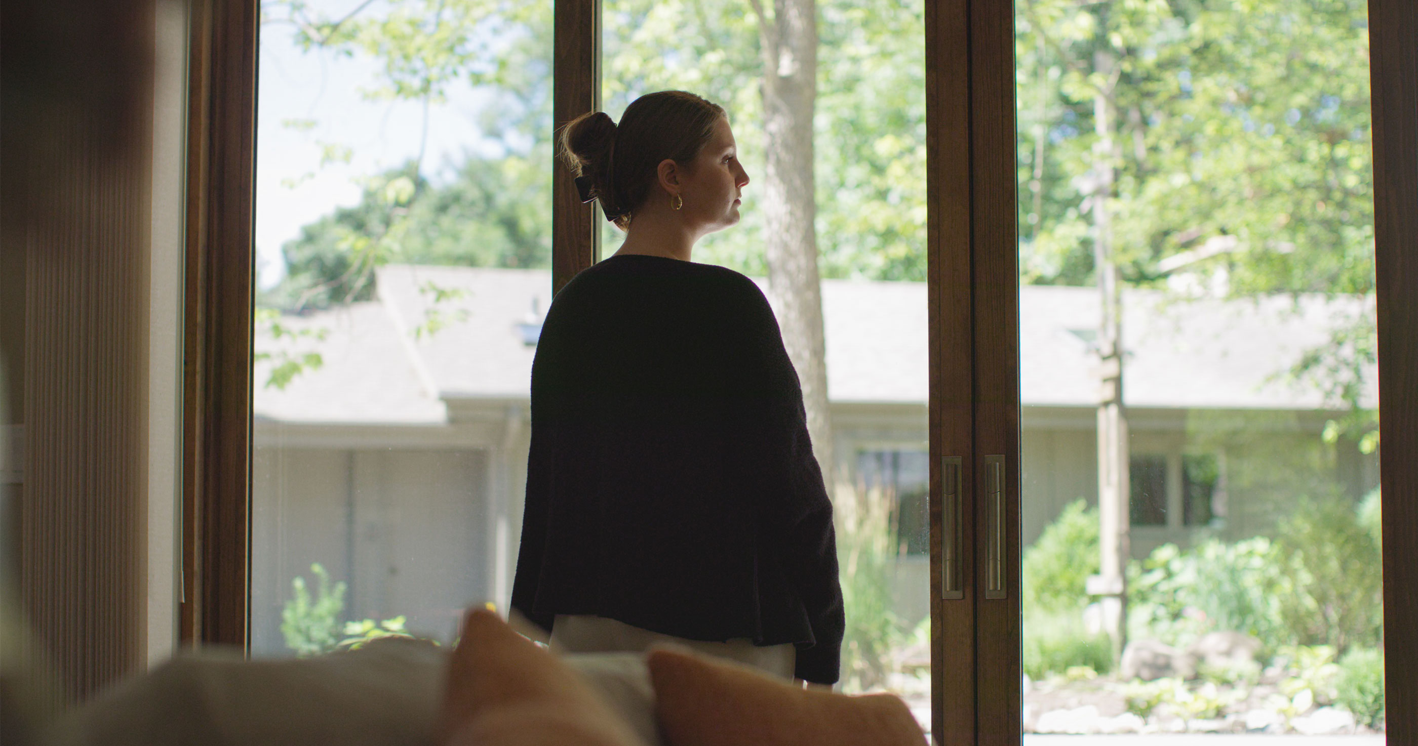 Lady looking at of the front window of a home.