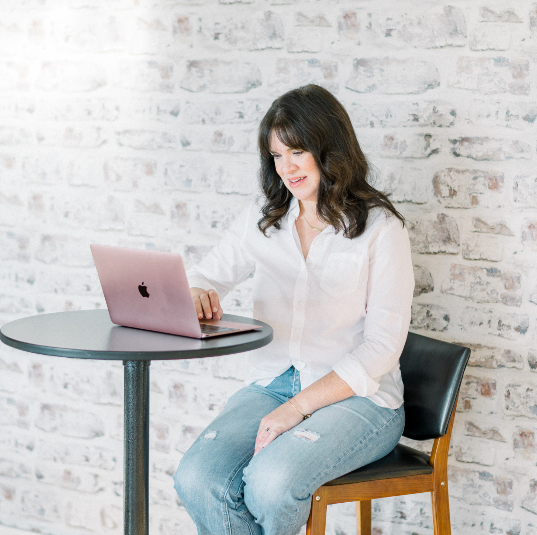 Women sitting at a small table with her lap top.