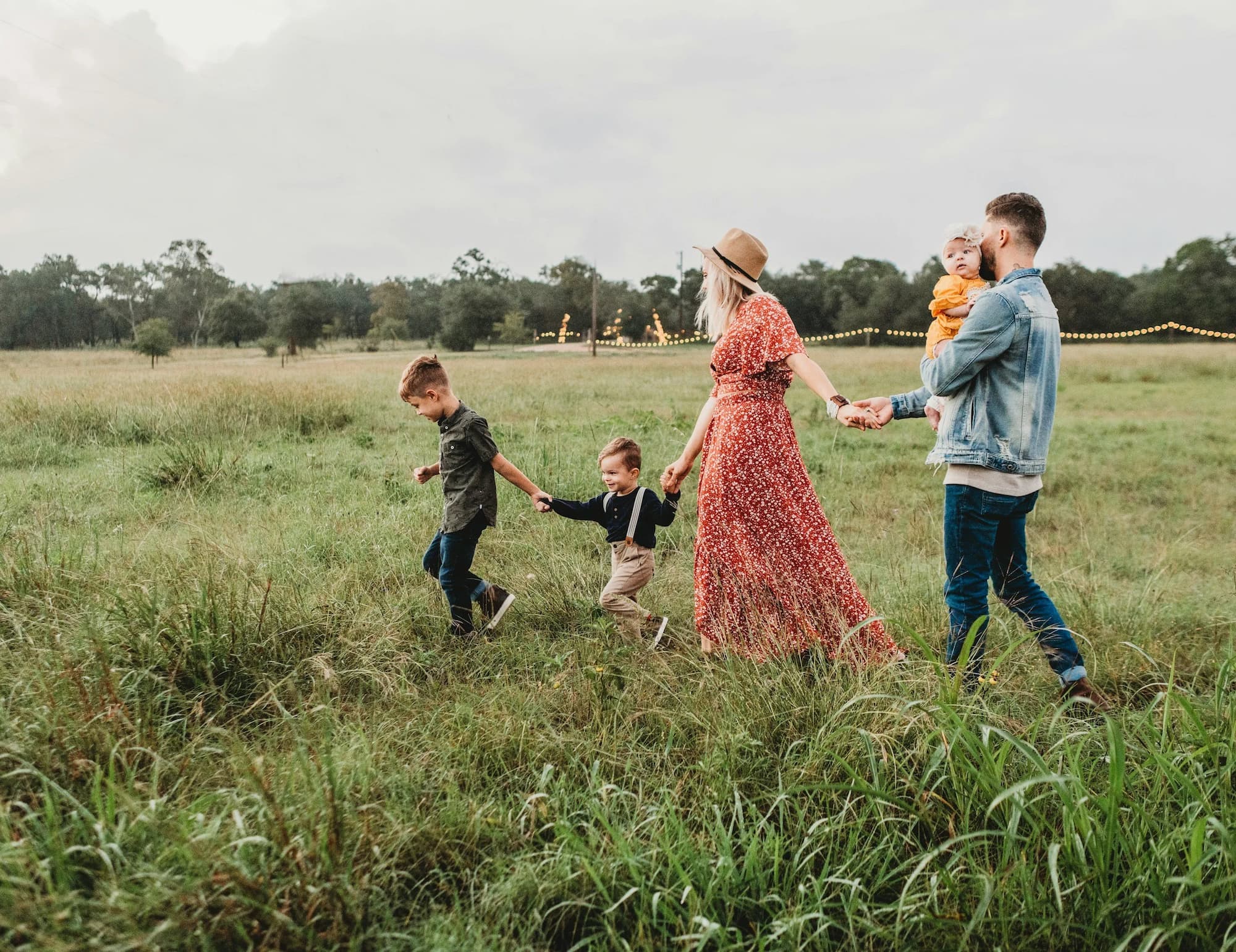 Family walking hand in hand through a field.