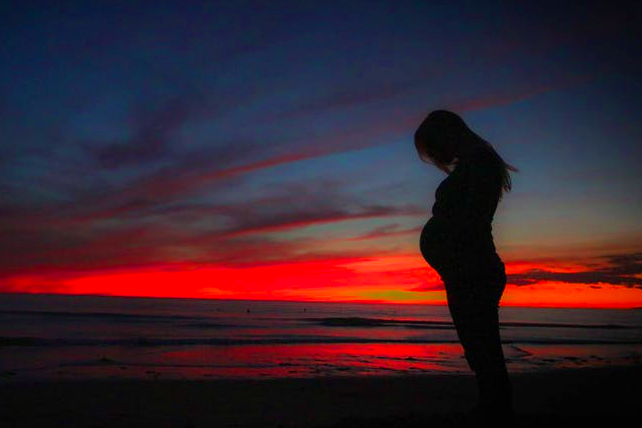 Pregnant woman with sunset in background.