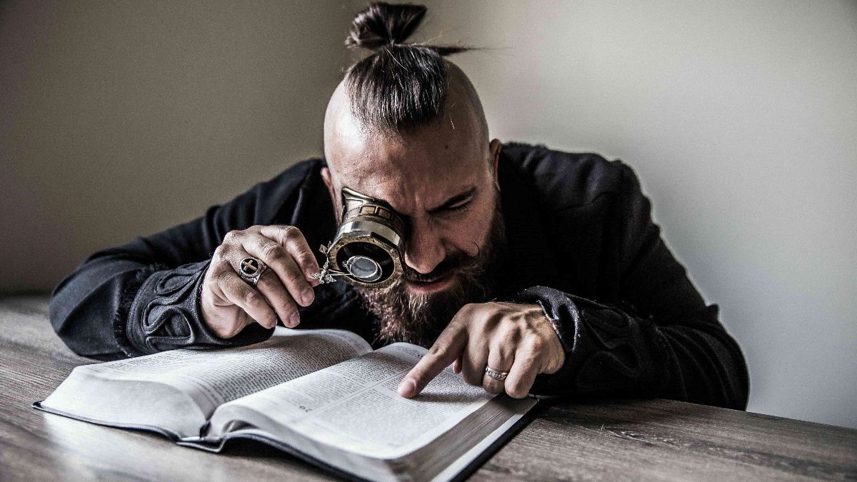 Guy uses magnifying glass to read book