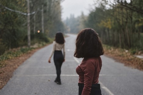 Woman Starting at Woman Walking Down the Road